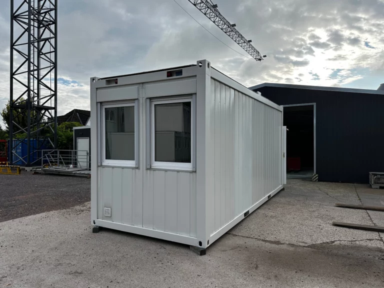 Bürocontainer 20 ft mit WC, zwei Fenstern an der Stirnseite und Außentür an der Längsseite, schräg von vorn.