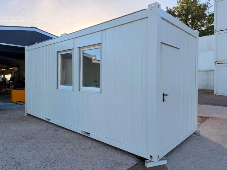 Weißer Bauleiter-Container 20 ft mit zwei Fenstern an der Längsseite und Tür an der Stirnseite.