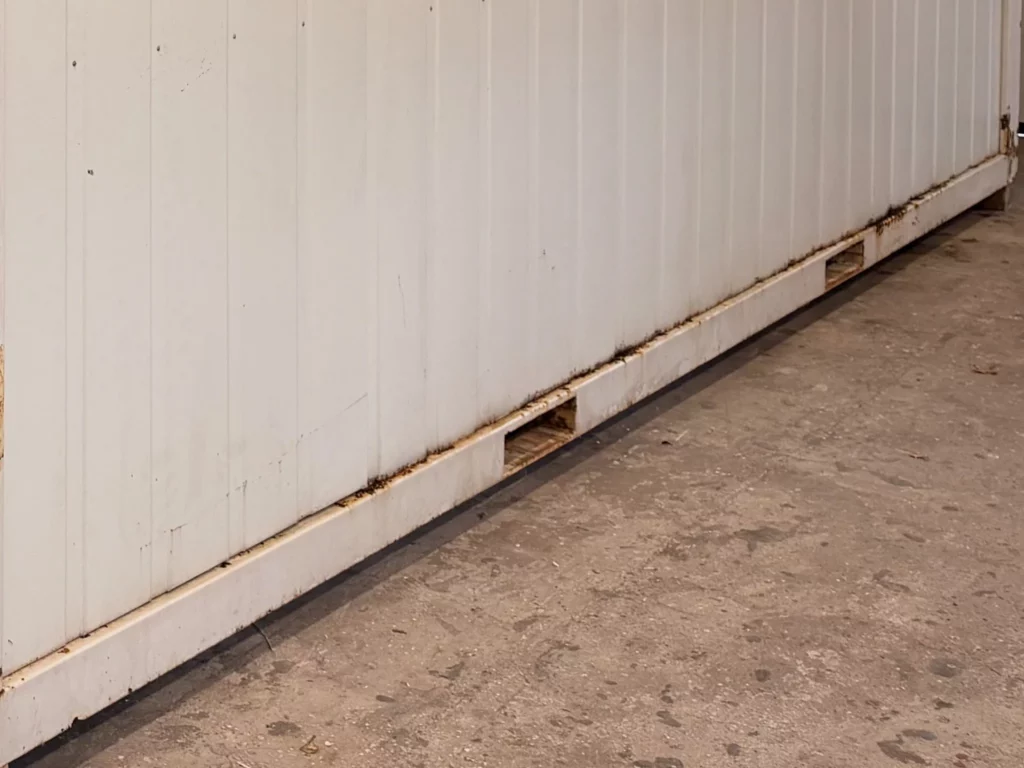 Längsseite eines gebrauchten Containers mit Rost entlang des Bodenrahmens und an den Staplertaschen
