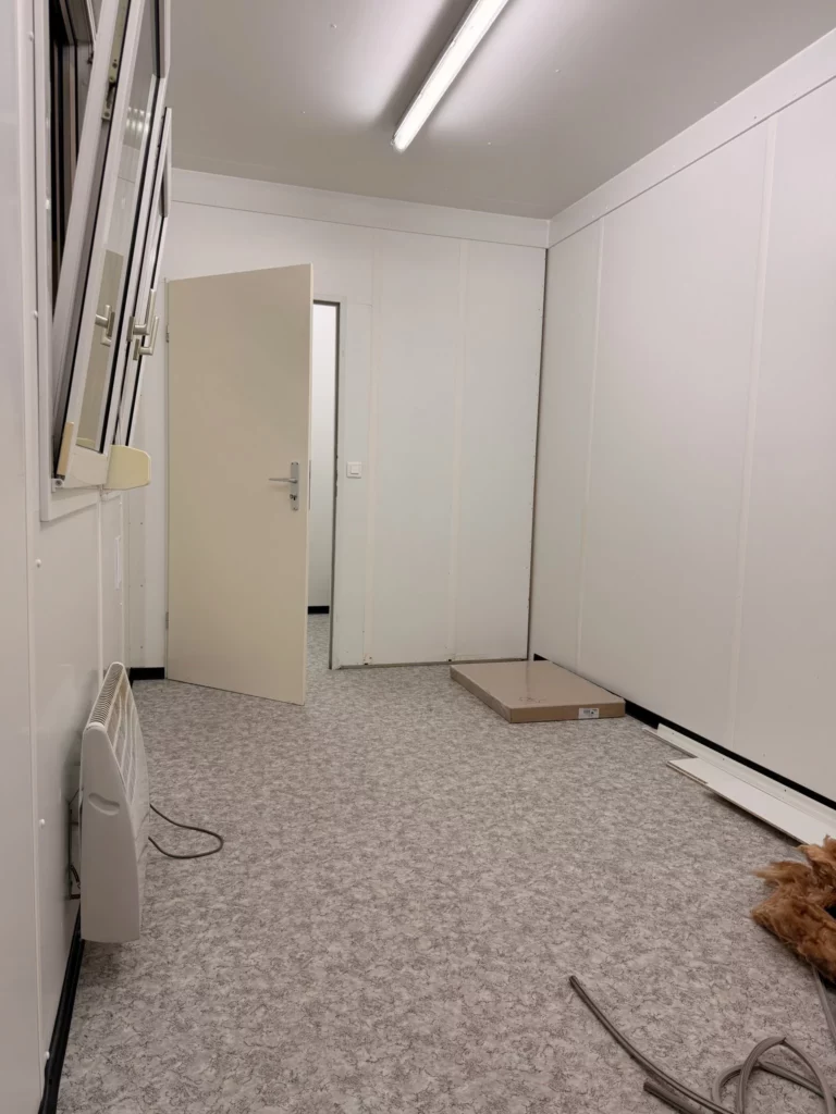 Büroraum im Ausbau mit Blick auf die neue Trennwand und die offene Innentür zum Nebenraum